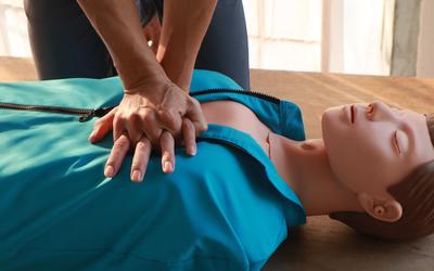 A person performs chest compressions on a CPR practice mannequin. 